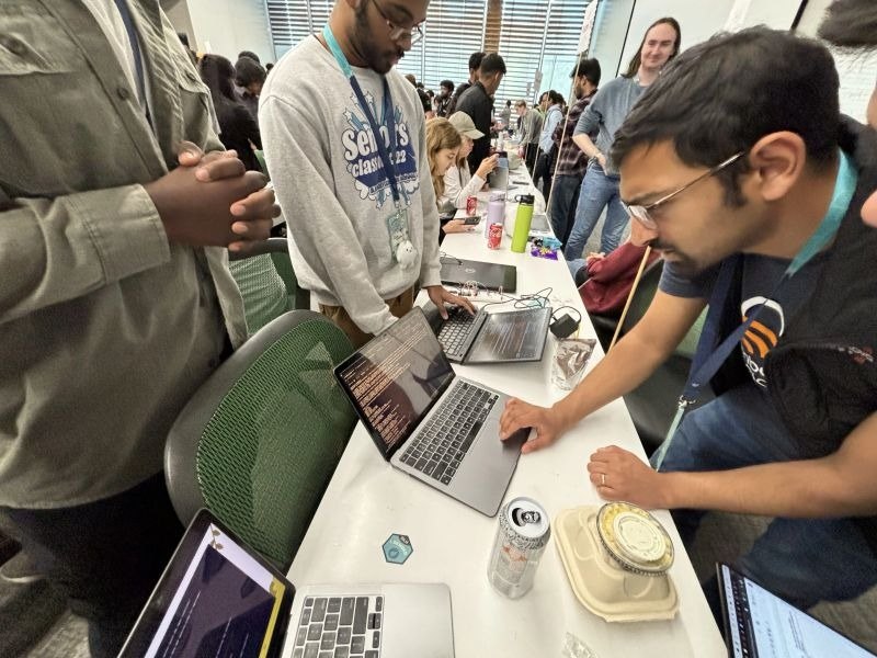 Developers gathered around a laptop and hardware project during the UTD hackathon.